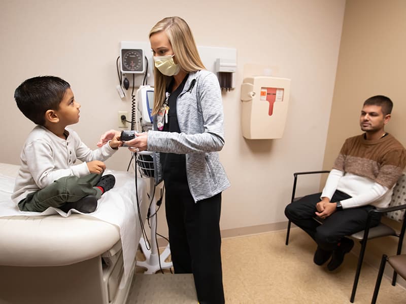 Registered nurse Sarah-Kate Rowan takes the vital signs of Children's of Mississippi Urgent Care patient Jaiden Patel of Brandon as his father, Jagnesh Patel, looks on.
